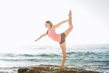 年轻白种的女性练瑜伽在海边