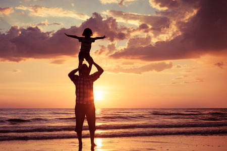 父亲和儿子在日落的时候在海滩上玩