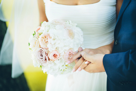 有粉红色的花朵在新郎和新娘手中的花束