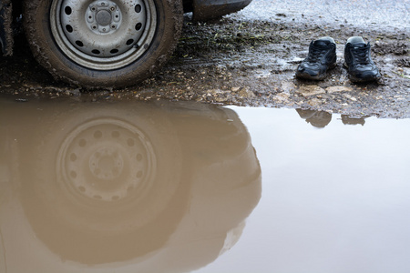 泥泞水坑中的反光轮车和男鞋