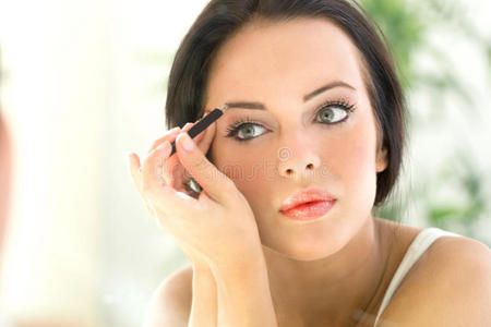 年轻漂亮的女人用眼睑涂抹眼线笔