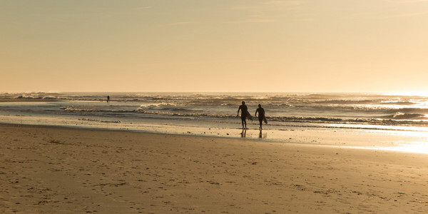 美丽的海景与冲浪者沿着海滩漫步
