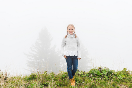 8岁的可爱小女孩在雾很大的时候在户外玩耍