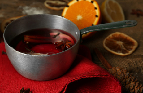 甜酒炖菜锅上装饰着红餐巾 肉桂和橙色的木制背景