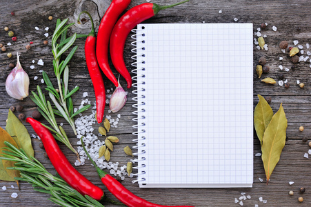 蔬菜和调料与打开笔记本的食谱上木制的背景