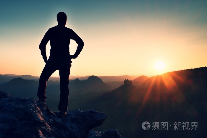 男人站在砂岩岩石在国家公园萨克森瑞士和看太阳美丽时刻的山峰上自然
