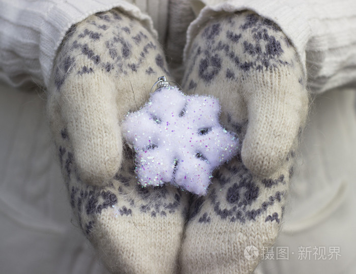 关闭了在针织的女性手上戴着手套在户外举行洁白的雪花