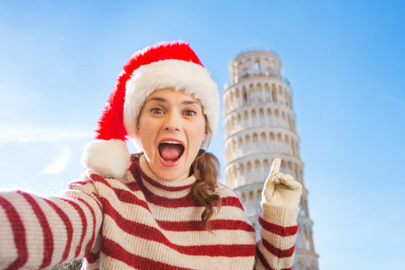 女人在圣诞老人的帽子以自拍照前靠旅游，比萨