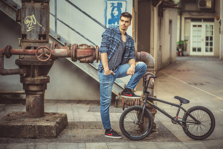 年轻人的时尚模特附近阁楼金属管和自行车