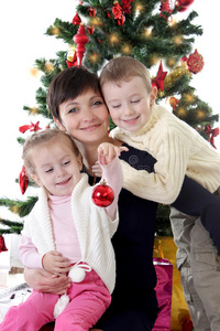 母亲和两个孩子在装饰圣诞树