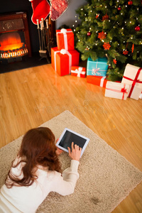 圣诞节红发女人躺在地板上用平板电脑
