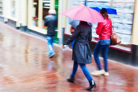 妇女带着伞走在多雨的城市