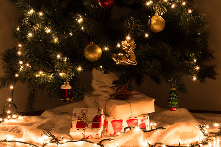 圣诞礼物在装饰的 gerlyandoy 之下, 明亮的黄色和红色球圣诞树