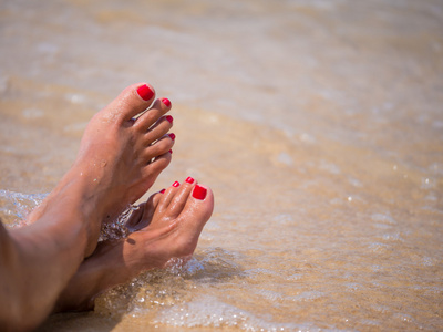 假期的概念。在海滩上放松的女人脚特写
