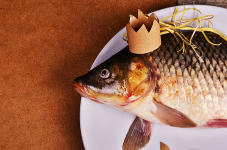 在木桌上戴着皇冠的鲤鱼。创意理念。鱼之王