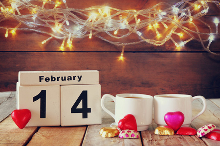 2 月 14 木制老式日历用多彩的心形状巧克力接下来到木制的桌子上几杯。选择性的焦点。老式过滤