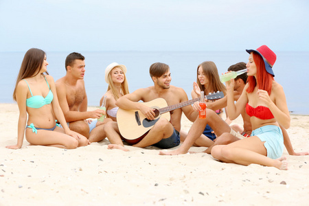美丽的年轻人与海滩上的吉他