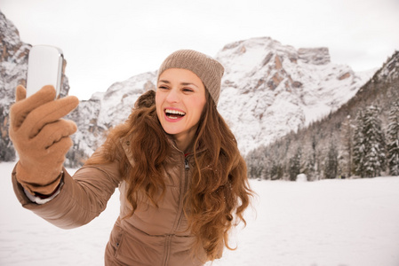 考虑自拍照在户外在白雪皑皑的群山中的年轻女子