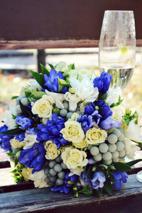 在木凳上的杏和蓝色玫瑰的美丽婚礼花束