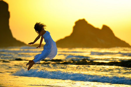 夏日夕阳光在海滩上的年轻女子图片