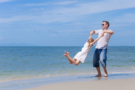 父亲和女儿在一天时间在沙滩上玩