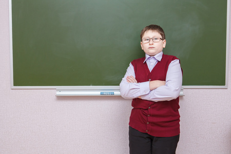男孩站在与他的双臂交叉在学校董事会