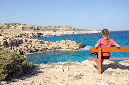 女孩坐在长椅上，看着地中海