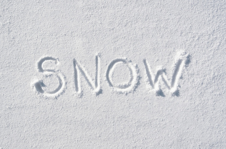 文字雪手写在雪背景上。 水平冬装