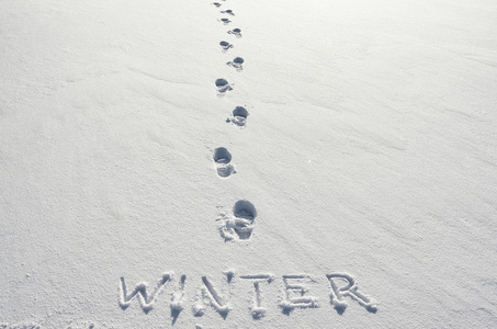 文字冬手写在雪地背景和脚步声上。