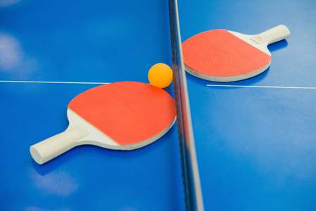 乒乓球球拍和球和蓝色乒乓球桌上的网