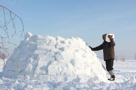 男子在冬天建立在雪林间空地上的一座冰屋