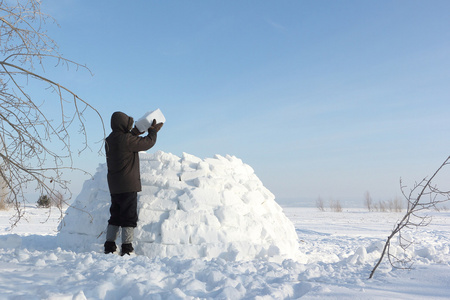 男子在冬天建立在雪林间空地上的一座冰屋