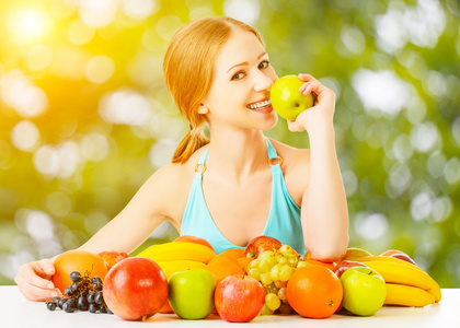 健康的素食食品。在夏天的幸福的女人吃苹果