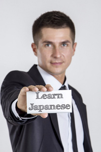 学习日本年轻商人拿着白色卡片与Tex