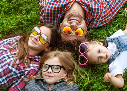 Papa und seine 3 Tchter liegen auf dem Rasen in Sonnenbrille gl