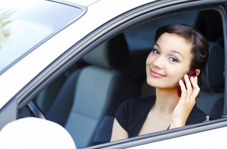 女人坐在一辆车和移动电话交谈