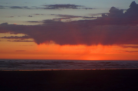 在海洋上的多云日落与前景中的波浪