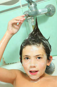 英俊的男孩洗他的头与洗发水