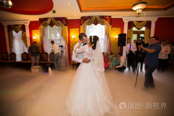 吻和舞蹈年轻新娘和新郎在黑暗的宴会大厅