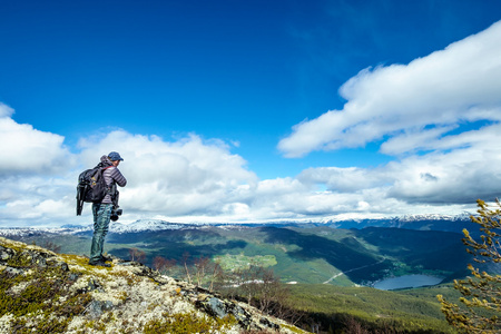 自然摄影师旅游用相机拍摄同时站在山顶。美丽的大自然挪威