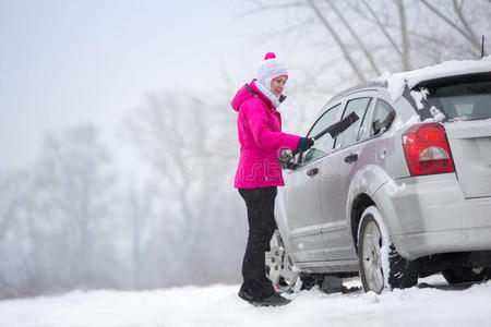 一位妇女在清理车上的雪