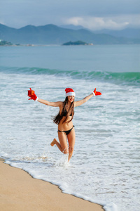 快乐的女孩带着圣诞礼物在海滩上奔跑