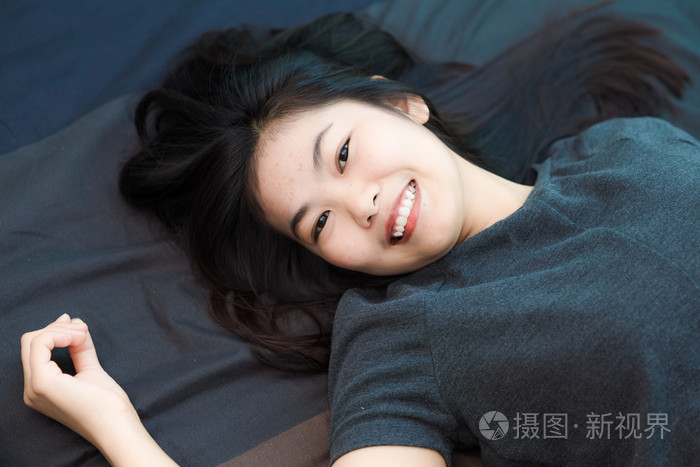 时尚的美丽年轻的亚洲女人躺在床上的照片