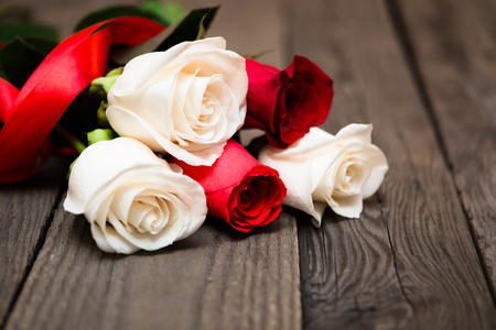 黑色木制背景上的红白玫瑰。 妇女日