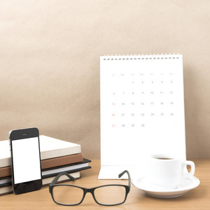 咖啡，电话，眼镜，堆栈的书和日历