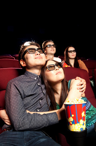 年轻夫妇坐在电影院里，看一部电影