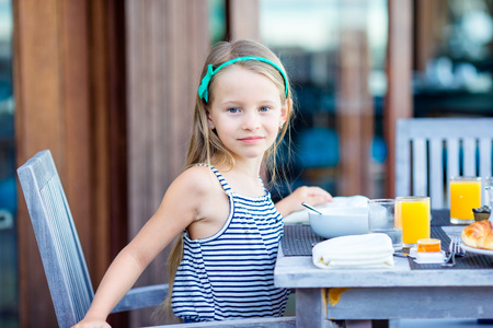 可爱的小女孩在户外咖啡馆吃早餐