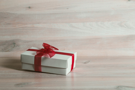 白色的木桌上的红丝带礼品盒