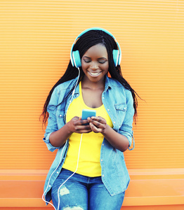 漂亮微笑非洲女人戴着耳机听音乐 ov