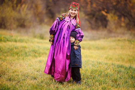 母亲和她的儿子在户外在传统的民族服装的家族肖像。秋天的颜色，亚洲的饰品
